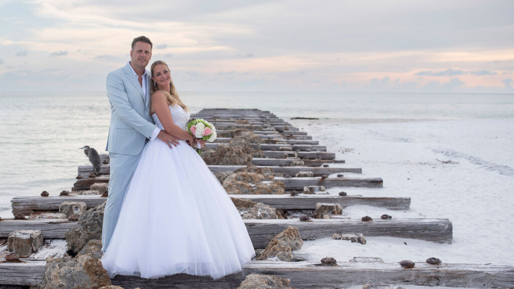 Photo showing wedding couple on pier on the beach relaxing after applying for their Florida marriage license by mail.